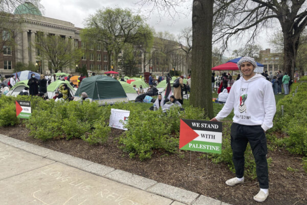 Ali Abu, a student at the University of Minnesota, poses for a photo in a white sweatshirt that says "Free Palestine" near an encampment at University of Minnesota in Minneapolis, Minn., Monday, April 29, 2024, during a protest over the Israel-Hamas war. The students are calling for universities to separate themselves from companies that are advancing Israel's military efforts in Gaza. (AP Photo/Trisha Ahmed)