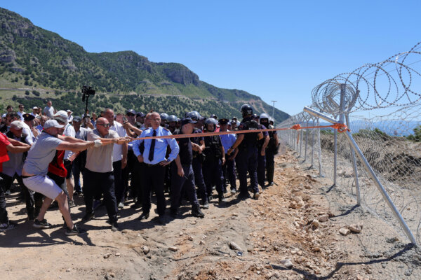 Protesters try to demolish a fence of a construction site during a rally against plans for building a tourist resort, in the Rrjoll area of Shkoder, northern Albania, Saturday, June 13, 2026. (AP Photo/Hameraldi Agolli)
