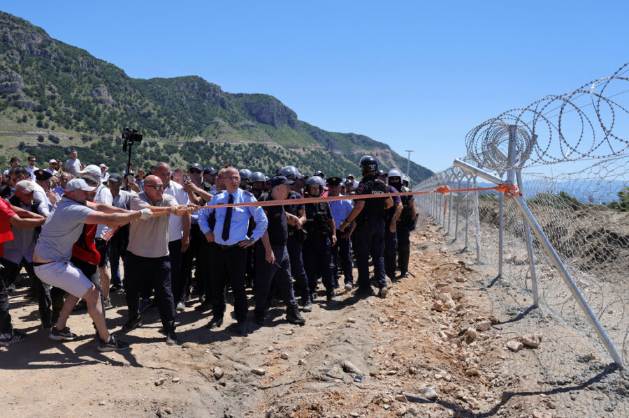 Protesters try to demolish a fence of a construction site during a rally against plans for building a tourist resort, in the Rrjoll area of Shkoder, northern Albania, Saturday, June 13, 2026. (AP Photo/Hameraldi Agolli)